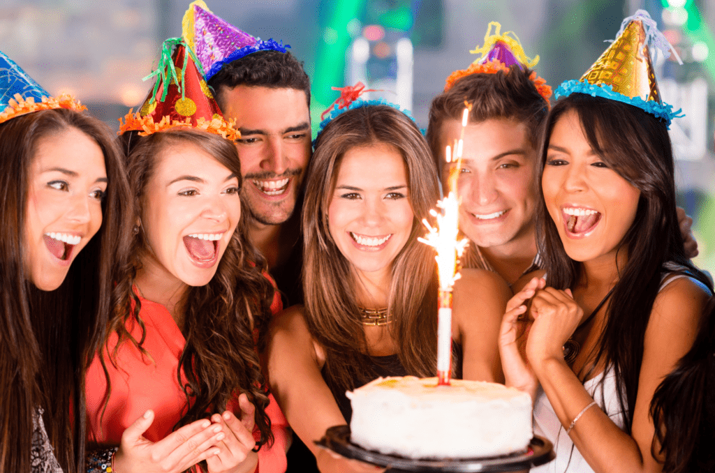 group of people celebrating birthday holding cake with candle