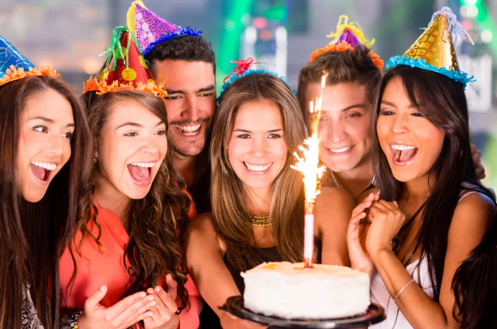 group of people celebrating birthday holding cake with candle